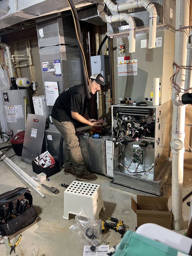 A technician working on an indoor HVAC unit in a basement at Rescue Heating and Air Conditioning in Manassas, VA