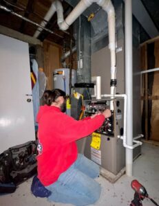 An Allegiance Heating & Air technician working on an indoor furnace or air handler in Greenville, IN.