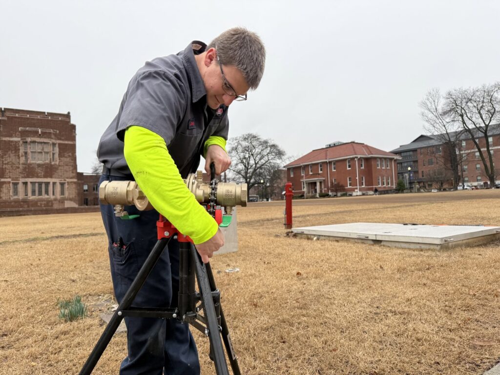 An Interstate AC technician working on a large outdoor plumbing valve assembly in Nashville, TN.