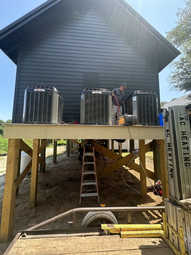 A technician working on multiple outdoor AC condenser units installed by AC Heating and Air Conditioning Services in Charleston, SC.