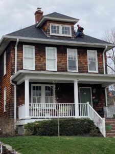 A K.P. Wildlife Control and Repairs LLC technician working on a residential roof in Annapolis, MD, likely for wildlife exclusion or repair.