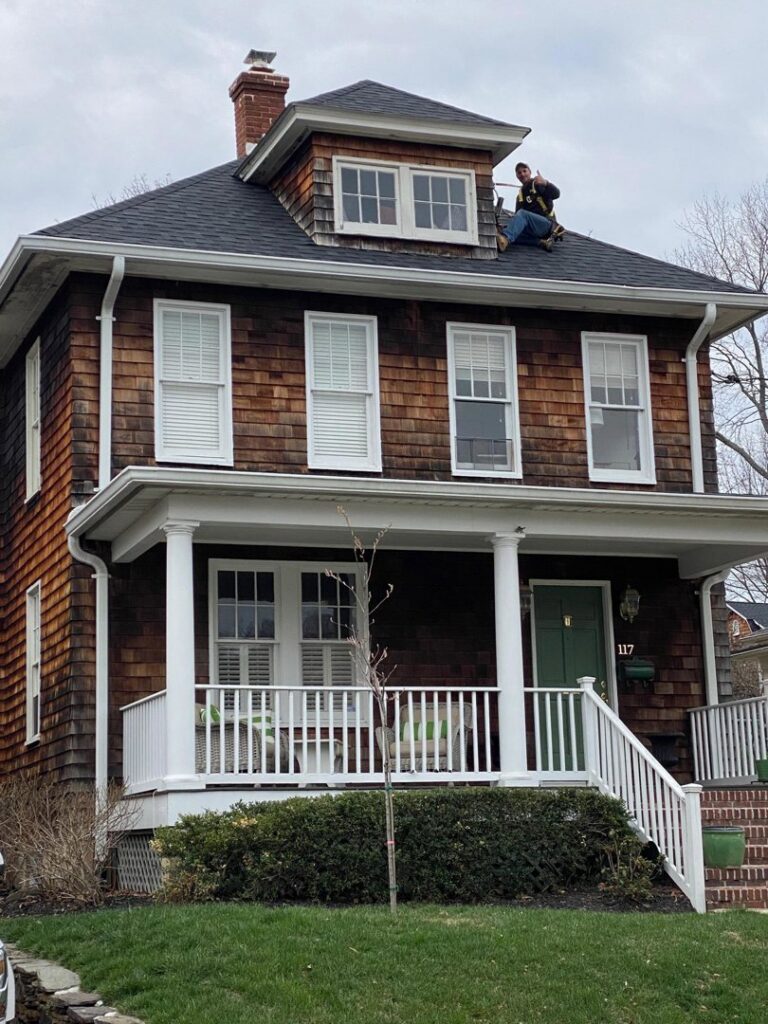 A K.P. Wildlife Control and Repairs LLC technician working on a residential roof in Annapolis, MD, likely for wildlife exclusion or repair.