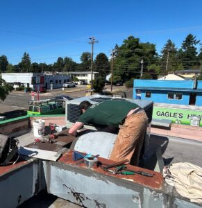 A Gagles Heating technician working on a commercial rooftop HVAC unit in Salem, OR.