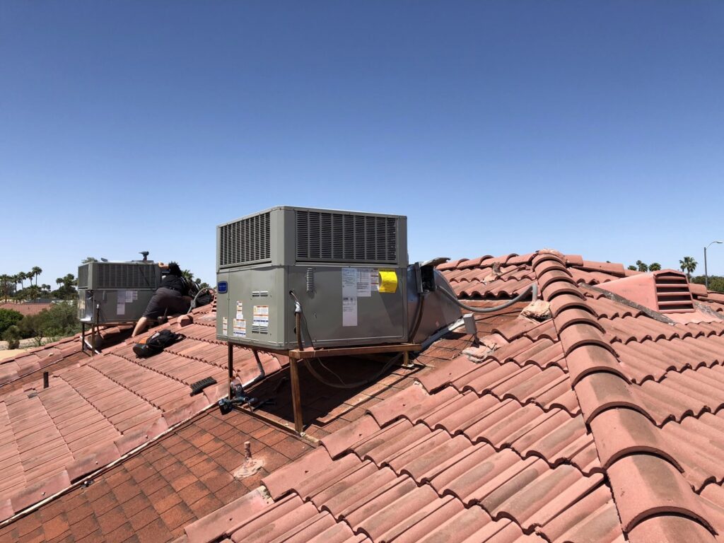 A technician performing work on a rooftop HVAC unit on a tiled roof for Hellerud Air in Peoria, AZ.