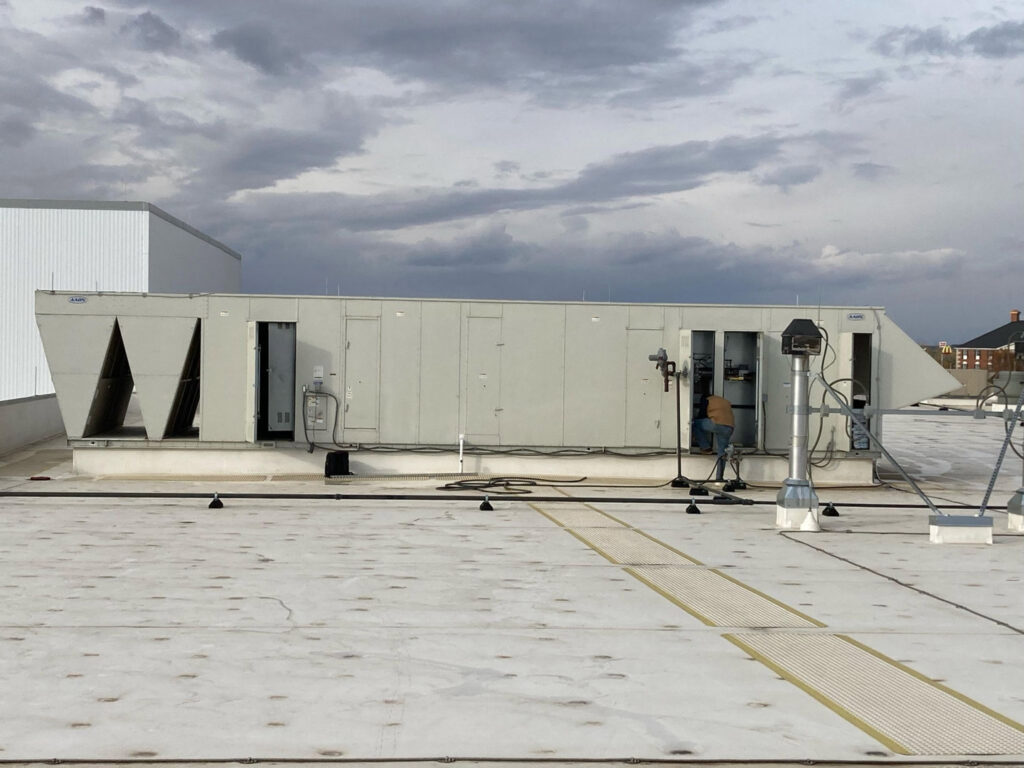 A technician working on a large commercial rooftop HVAC unit for Schomp's Mechanical Services in Brookings, SD.