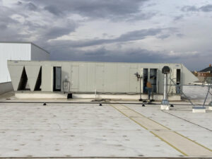 A technician working on a large commercial rooftop HVAC unit for Schomp's Mechanical Services in Brookings, SD.