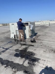 A Modern Air Services technician performing maintenance on a rooftop HVAC unit in Fort Worth, TX.