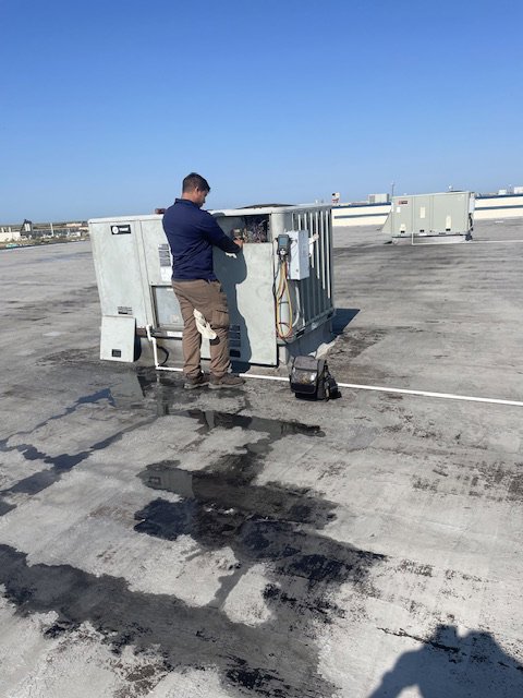 A Modern Air Services technician performing maintenance on a rooftop HVAC unit in Fort Worth, TX.