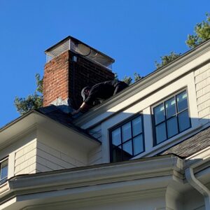 A technician from Boston Air Ducts Cleaning working on a roof vent or chimney in Newton, MA.
