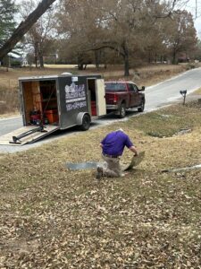 A Milan Heating & Air technician working with sheet metal for an HVAC project next to a service trailer in Milan, TN.
