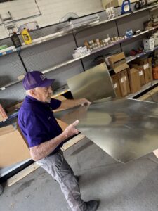 An experienced Milan Heating & Air technician working with a large sheet of metal for ductwork fabrication in Milan, TN.