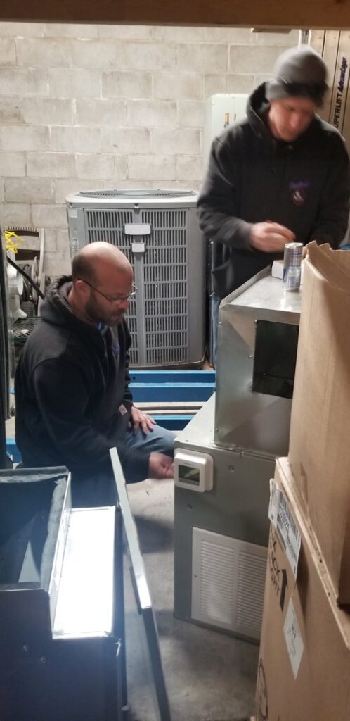 Two technicians assembling an HVAC unit in the workshop at Frederick Plumbing, Heating & Air Conditioning in Wichita, KS