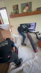 SafeAir Duct & Chimney technicians performing a chimney sweep and cleaning service on a fireplace in Dallas, TX.