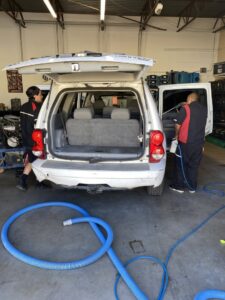 Two technicians professionally cleaning the interior of a white SUV at Steamway Carpet Cleaning in El Paso, TX
