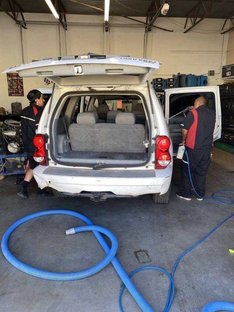Two technicians professionally cleaning the interior of a white SUV at Steamway Carpet Cleaning in El Paso, TX