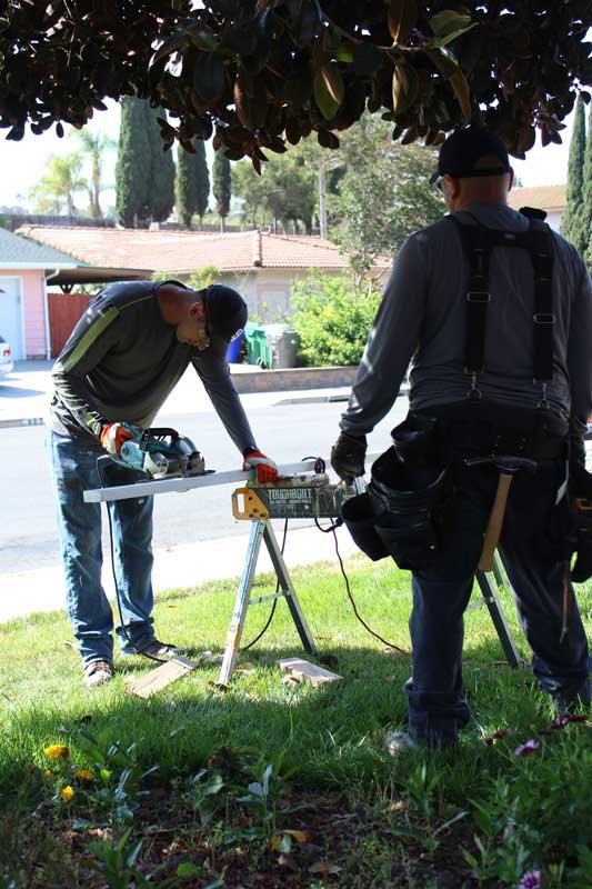Two technicians cutting wood for repairs, likely related to termite damage, for United Termite Control in San Marcos, CA.
