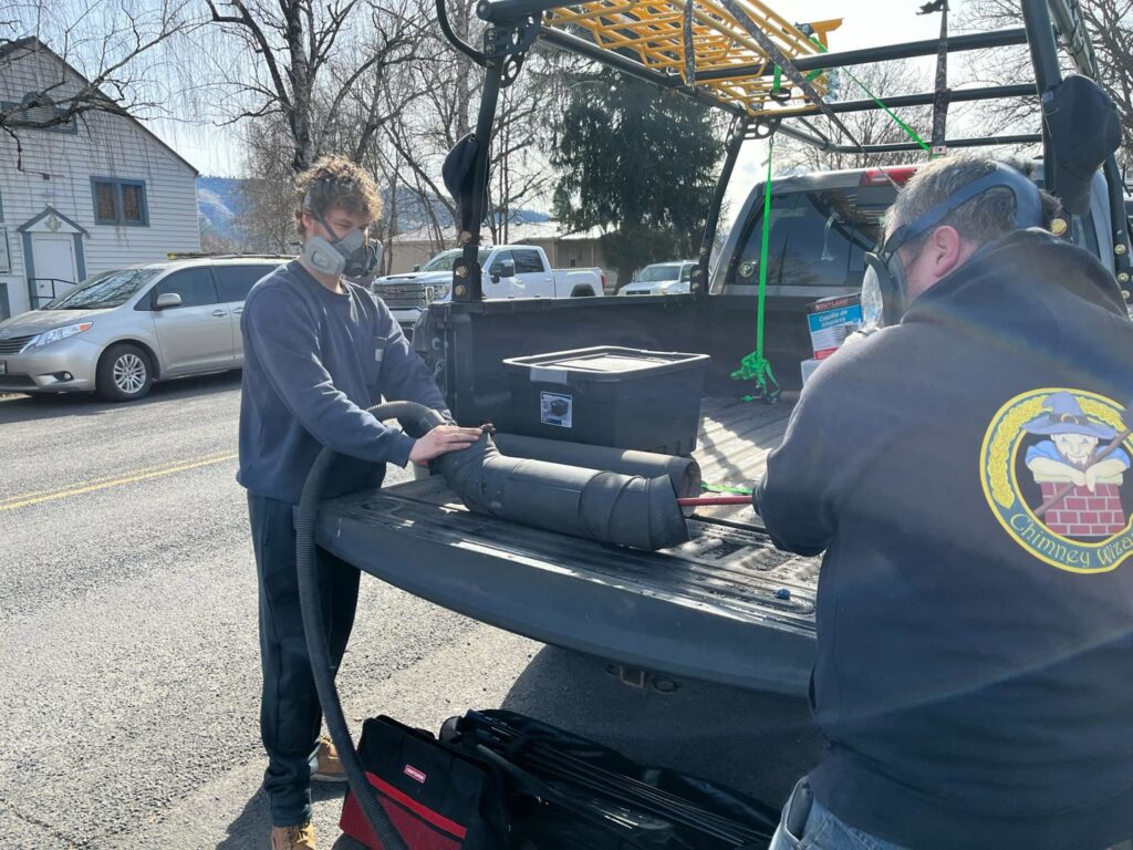Chimney Wizards LLC technicians handling chimney sweep equipment from their truck, preparing for a job in Orofino, ID.