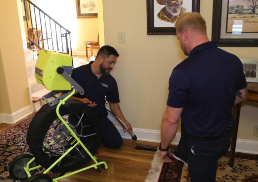 Two Air Doctor Duct Cleaning & Lining technicians inspecting a floor vent with specialized camera equipment in a home in Tulsa, OK.