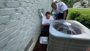 Two technicians inspecting an outdoor HVAC unit with diagnostic tools for Parks Heating Cooling Plumbing & Electrical in Indian Trail, NC