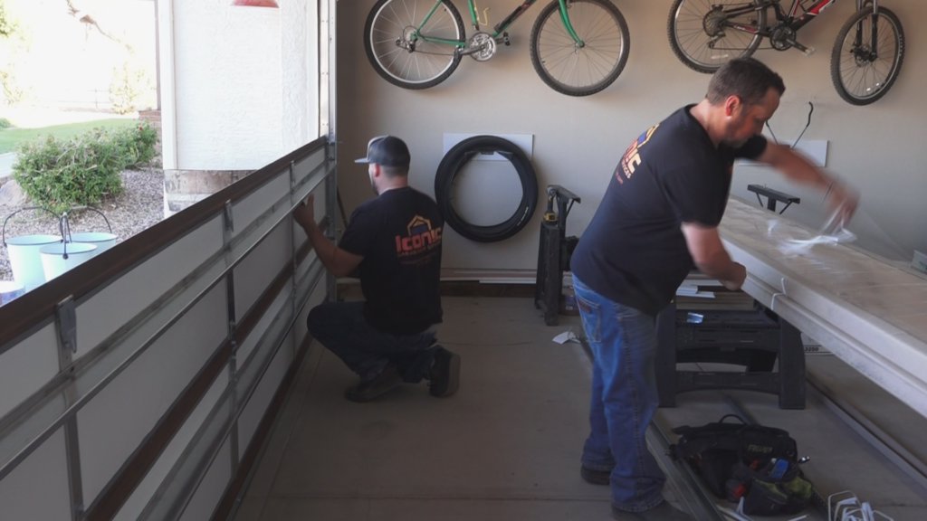 Two technicians from Iconic Garage Door Service installing garage door panels inside a residential garage in Queen Creek, AZ