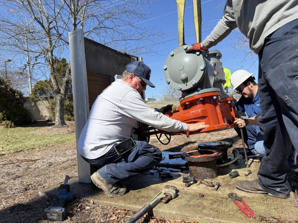 Interstate AC technicians installing a large industrial pump or valve assembly outdoors in Nashville, TN.