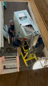 Air Care Heating and Cooling Services technicians installing a large indoor HVAC unit in Shreveport, LA.