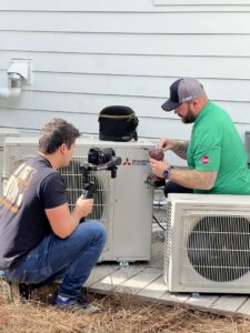 Two Green Dot Heating & Air technicians installing Mitsubishi Electric mini-split units at a home in Wilmington, NC.