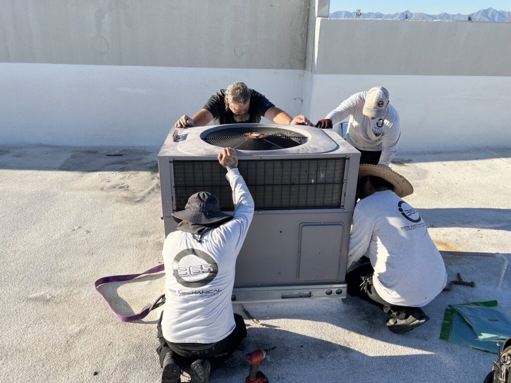 Four technicians installing a new rooftop HVAC unit on a commercial building for 365 Mechanical in Mesa, AZ.