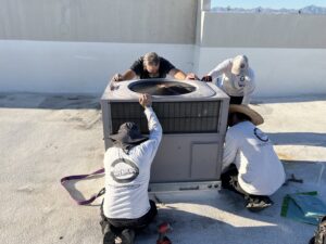 Four technicians installing a new rooftop HVAC unit on a commercial building for 365 Mechanical in Mesa, AZ.