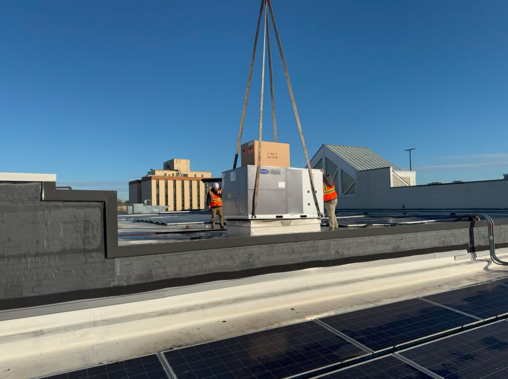 Technicians installing a new rooftop HVAC unit with a crane on a commercial building for APEX HVAC Solutions LLC in Frederick, MD.