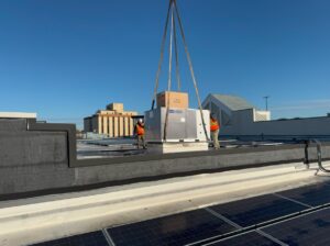 Technicians installing a new rooftop HVAC unit with a crane on a commercial building for APEX HVAC Solutions LLC in Frederick, MD.