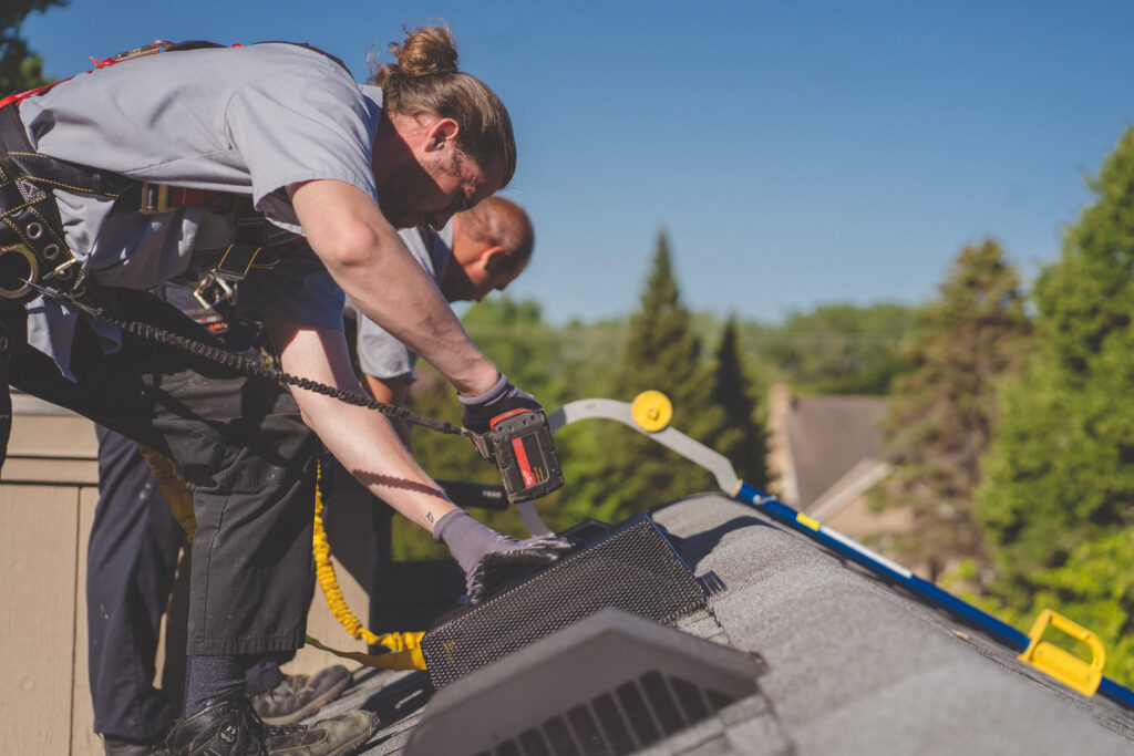 Two technicians installing a roof vent for wildlife exclusion at Abra Kadabra Pest and Wildlife in Forest Lake, MN.