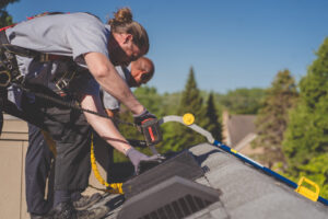 Two technicians installing a roof vent for wildlife exclusion at Abra Kadabra Pest and Wildlife in Forest Lake, MN.