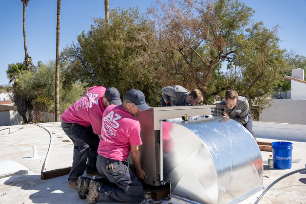HVAC technicians from AZ Perfect Comfort installing a rooftop air conditioning unit on a home in Phoenix, AZ.