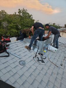 Multiple technicians installing a new rooftop HVAC unit and ductwork on a shingle roof for Colton Air Conditioning - Las Vegas in Las Vegas, NV.