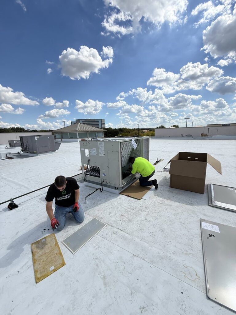 Community Mechanical technicians installing a commercial rooftop HVAC unit in Plano, TX.