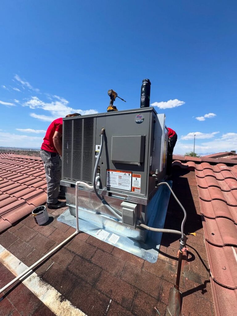 Two technicians installing a new rooftop HVAC unit on a residential tiled roof by Cool Camel HVAC in Henderson, NV
