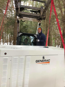 Technicians using heavy machinery to move a Generac Protector OS generator for installation by Great Lakes Power Generation in Williamsburg, MI.