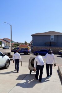 Ignitify Commercial Grade HVAC technicians moving an outdoor HVAC unit on a dolly in El Paso, TX.