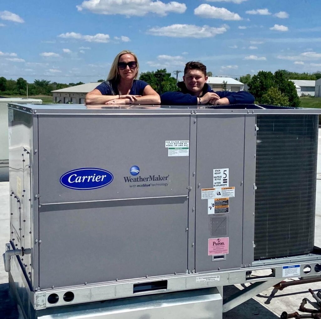 Two technicians from A All Temp Inc. Heating & Cooling on a commercial rooftop HVAC unit in Naperville, IL.