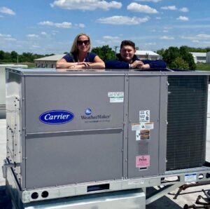 Two technicians from A All Temp Inc. Heating & Cooling on a commercial rooftop HVAC unit in Naperville, IL.