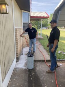 Two technicians from Roach's Termite Service Inc. preparing for pest treatment outside a home in Oklahoma City, OK