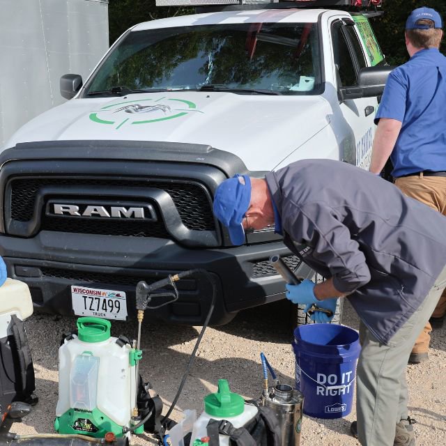 Pest control technicians preparing sprayers and equipment next to a company truck for 1st Choice Pest Solutions in Eau Claire, WI.