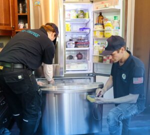 Two Mr. Fridge technicians repairing a residential refrigerator in a home in Seattle, WA.