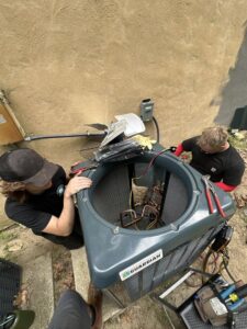 Two technicians servicing an outdoor Guardian air conditioning unit for Green Mechanical LLC in Philadelphia, PA.