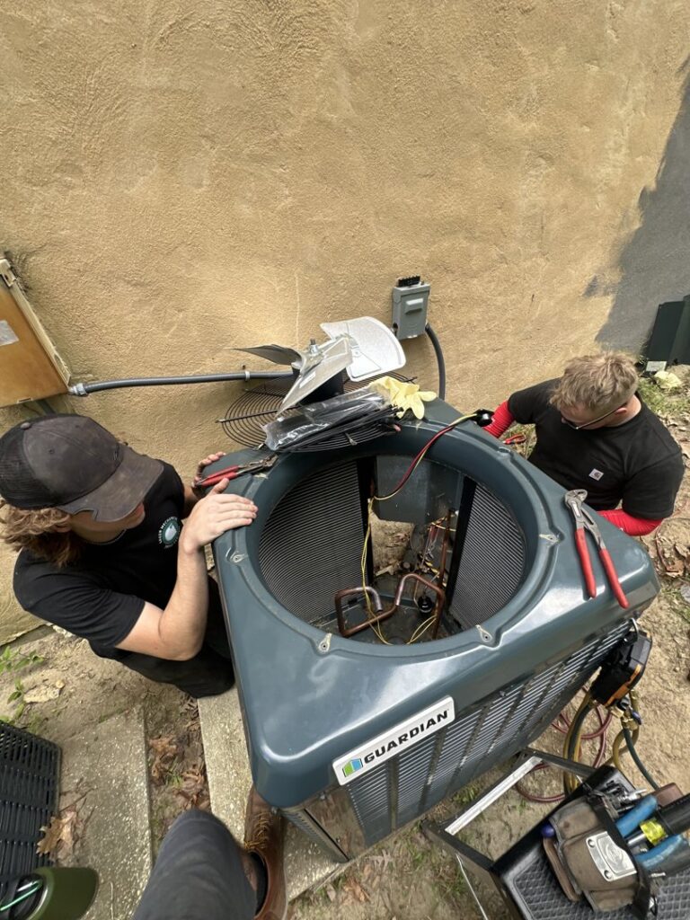 Two technicians servicing an outdoor Guardian air conditioning unit for Green Mechanical LLC in Philadelphia, PA.