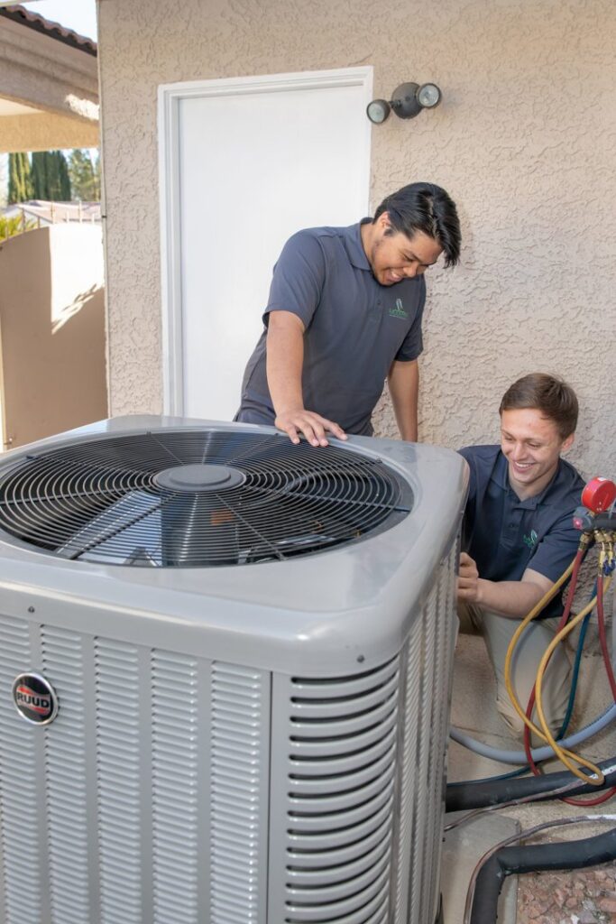 Two Modern Air Conditioning & Heating technicians servicing an outdoor AC unit in Boulder City, NV.