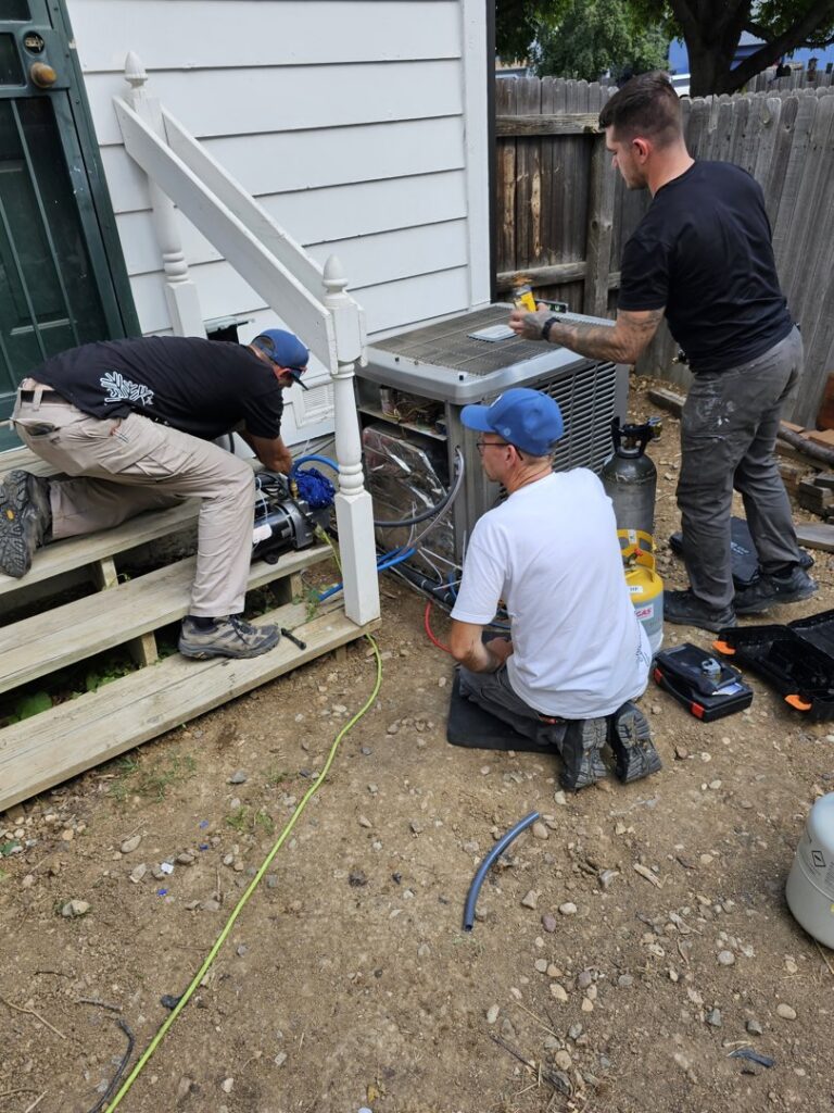 Three technicians servicing an outdoor air conditioning unit for True Heating and Cooling in Greenfield, IN.