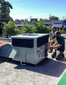 Two Gagles Heating technicians servicing a commercial rooftop HVAC unit in Salem, OR.