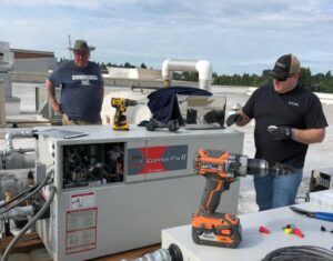 Two technicians from Cummings Inc. servicing a commercial rooftop HVAC unit in Puyallup, WA.